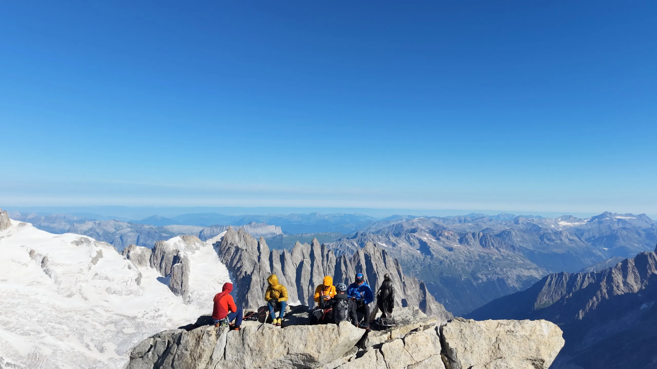 A party of five climbers resting on the summit block of the Dent du Géant.
